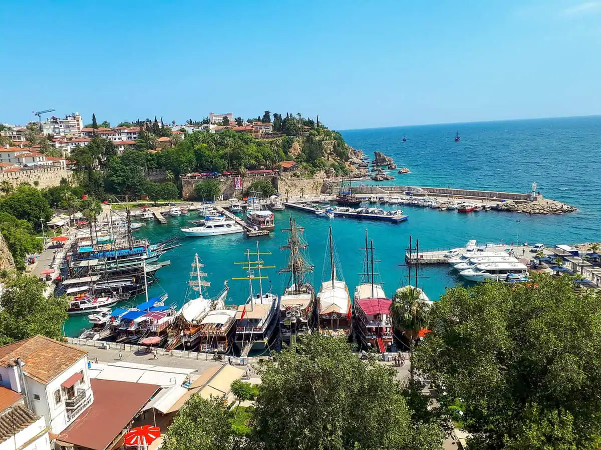Tour boats moored in the turquoise water of Kaleici Roman harbour beneath the old town cliffs