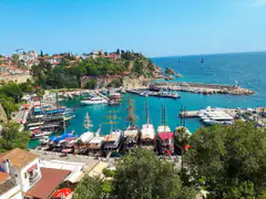 Tour boats moored in the turquoise water of Kaleici Roman harbour beneath the old town cliffs