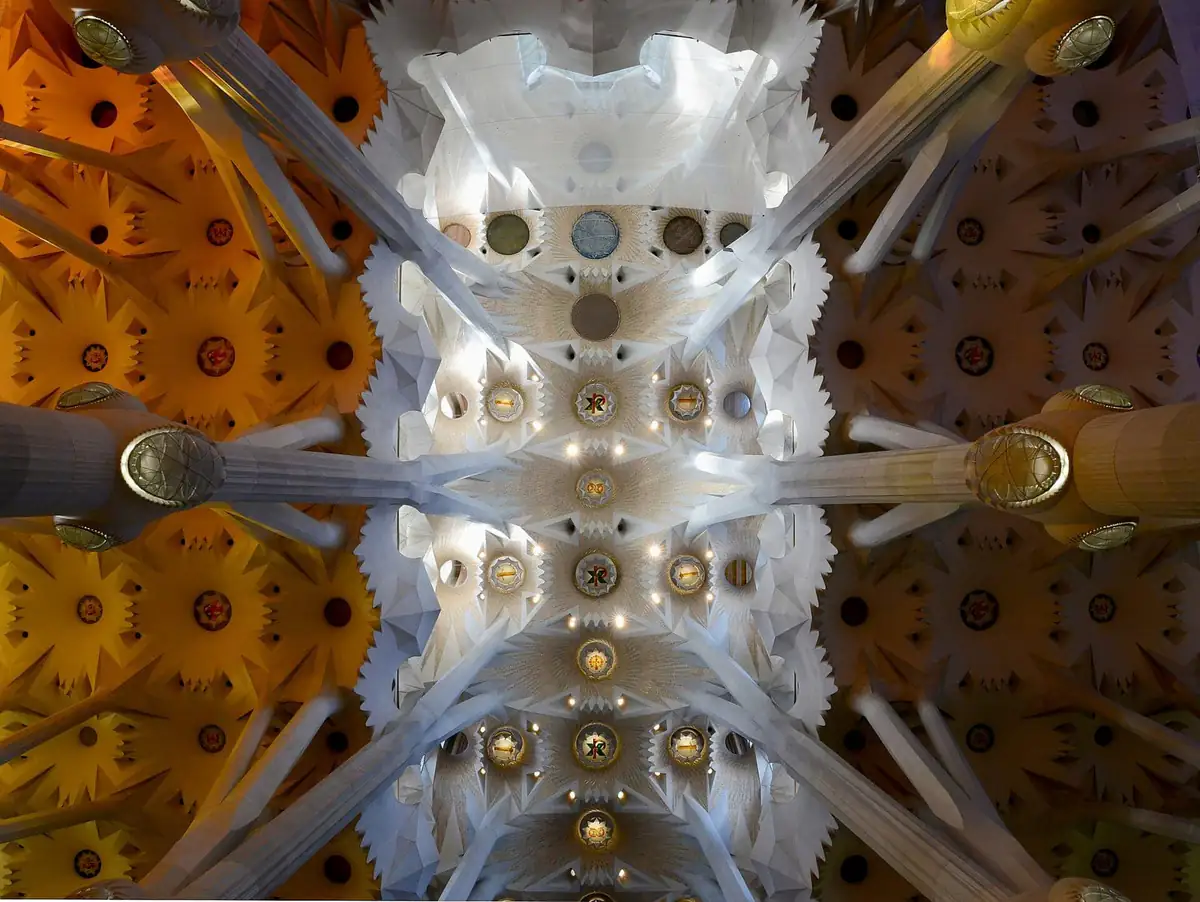 Looking up at the tree-like columns and colorful vaulted ceiling inside the Sagrada Familia