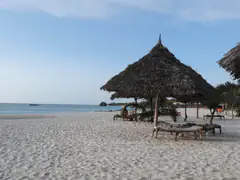 White sand, thatched umbrellas and calm blue sea on Kendwa beach, Zanzibar
