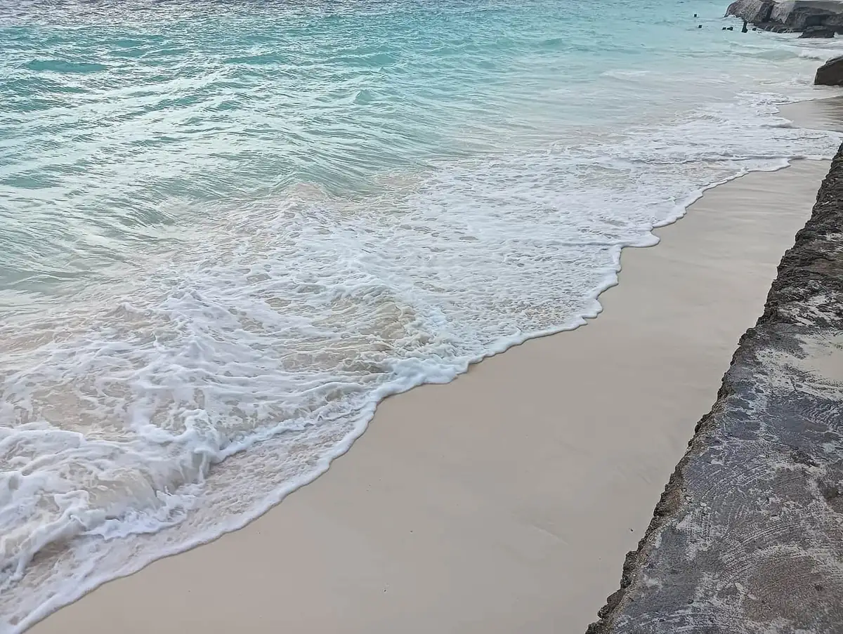 Surf washing over white sand beside coral rock at Nungwi