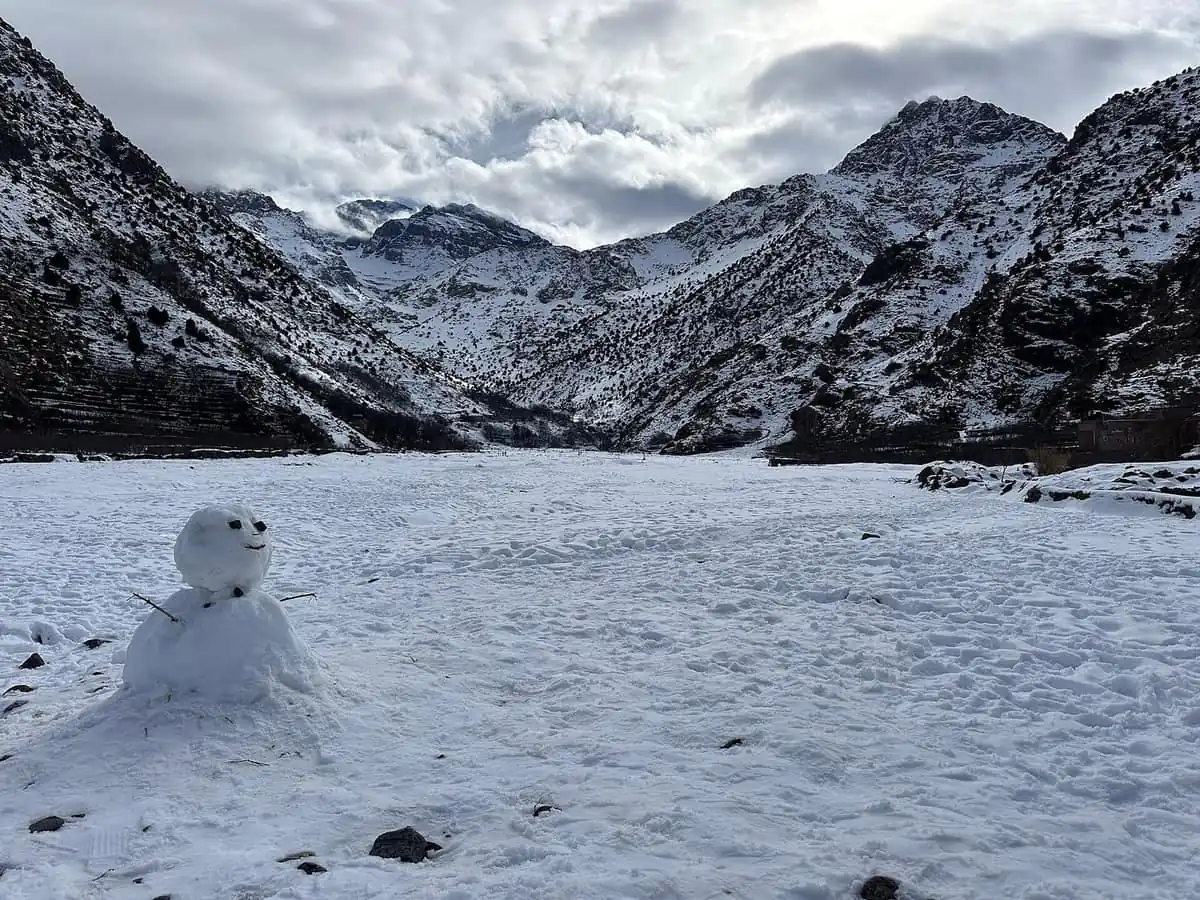 Snow-covered valley in the High Atlas mountains with a small snowman in the foreground