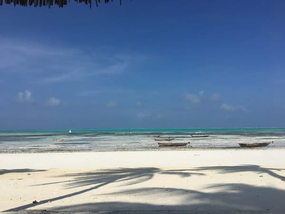 White sand and fishing boats on calm turquoise water at Jambiani beach