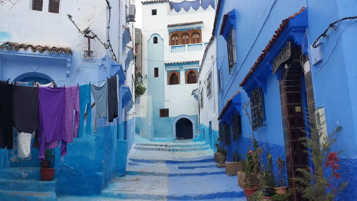 A blue-painted lane in Chefchaouen with laundry hanging across the street