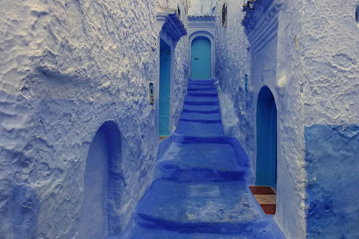 A narrow stepped alley painted blue in Chefchaouen with blue doors