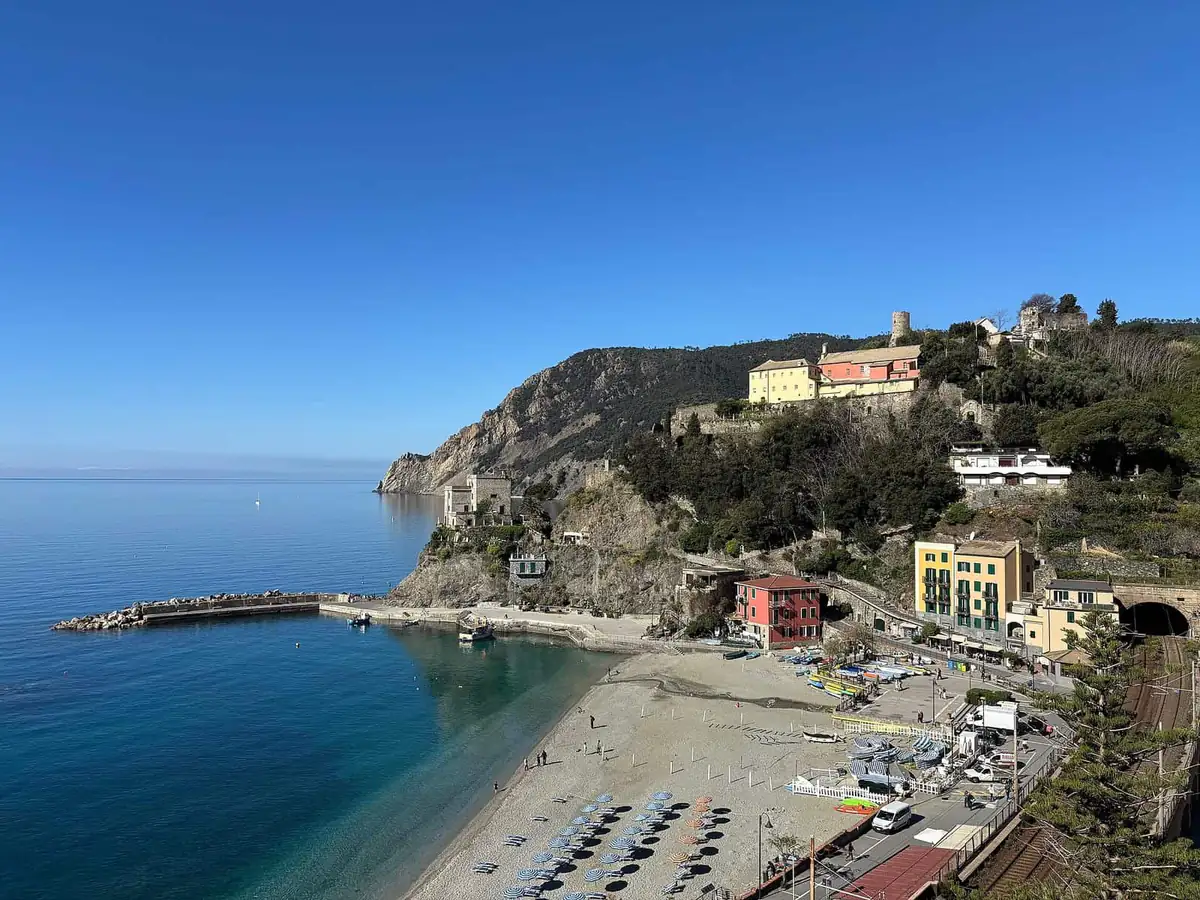 Monterosso al Mare beach with striped umbrellas and the old town on the headland