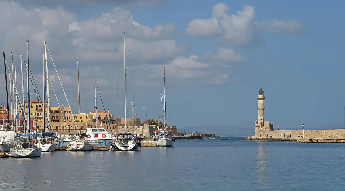 Boats moored in Chania harbour with the stone lighthouse at the end of the breakwater