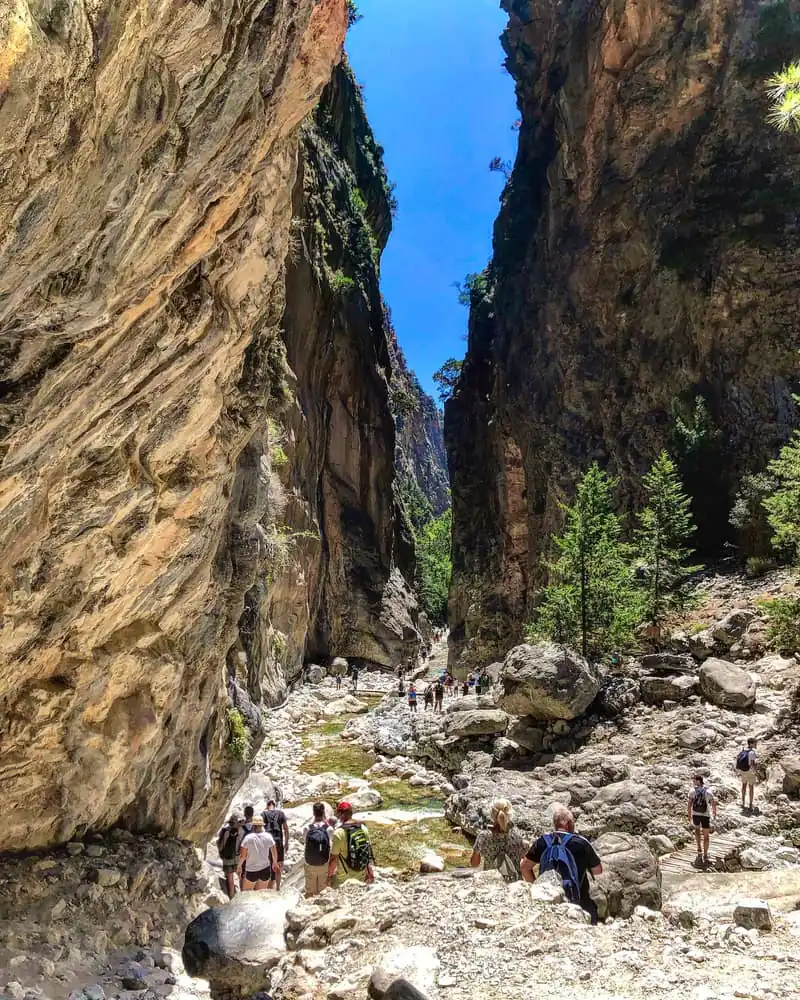 Hikers walking through the narrow rocky bed of the Samaria Gorge in Crete