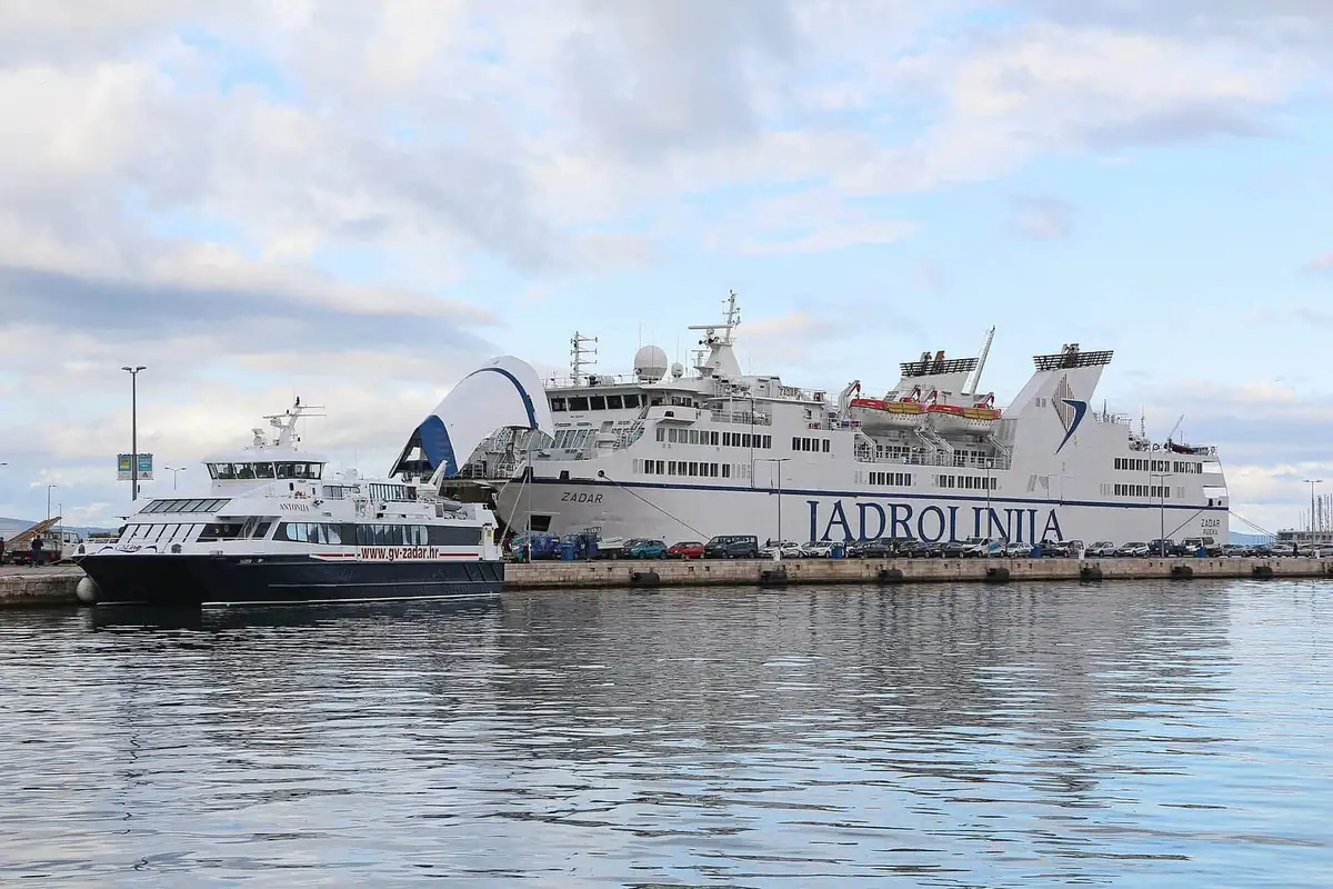 A white Jadrolinija car ferry and a smaller passenger catamaran tied up at Split ferry port
