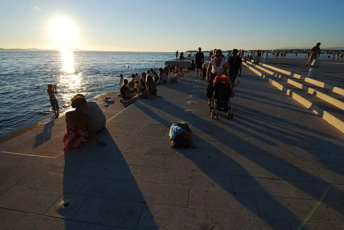 People sitting on the Sea Organ steps at sunset in Zadar