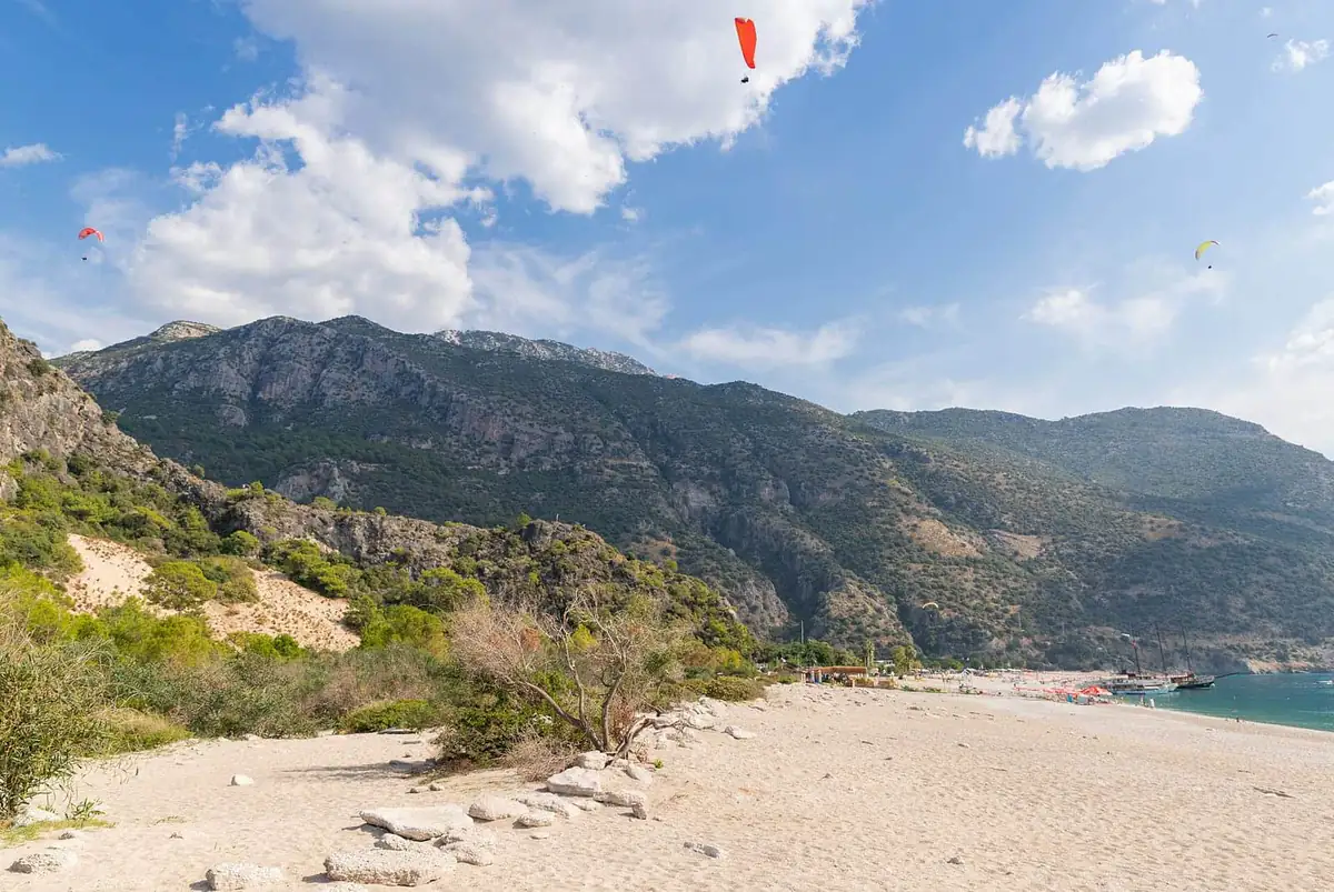 Paragliders descending towards the beach below the forested slopes of Babadağ near Ölüdeniz