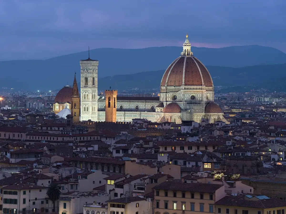 The Florence Duomo lit up at night, seen over the city rooftops