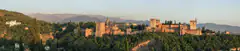 The Alhambra palace complex in Granada glowing at golden hour, with the Sierra Nevada mountains behind