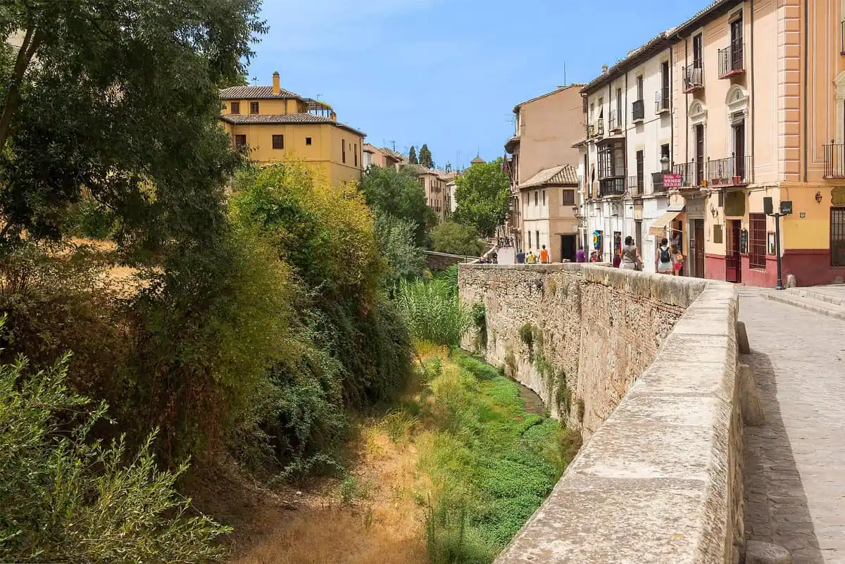 The Carrera del Darro in Granada, with the river channel and old houses on a sunny day