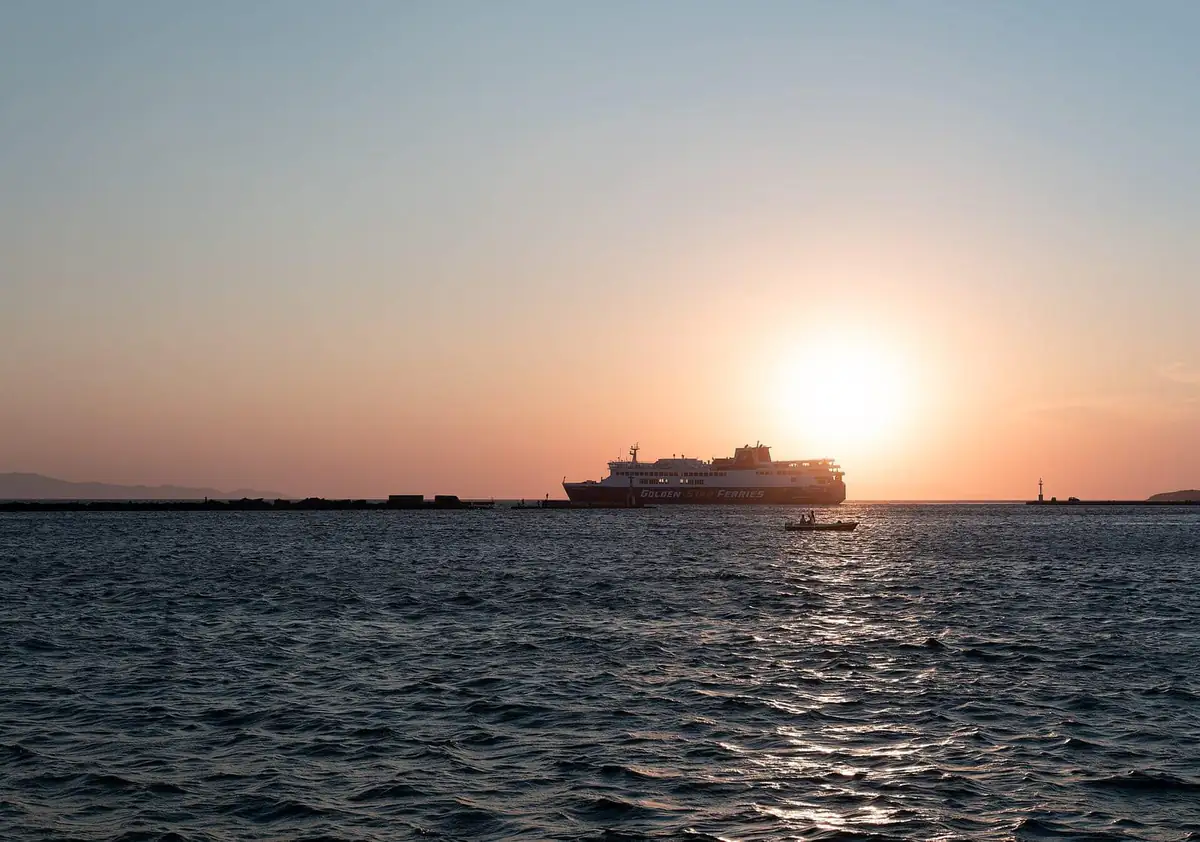 A large ferry leaving the port of Tinos at sunset