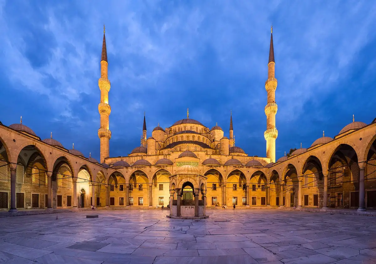 The floodlit courtyard and six minarets of the Blue Mosque at dusk