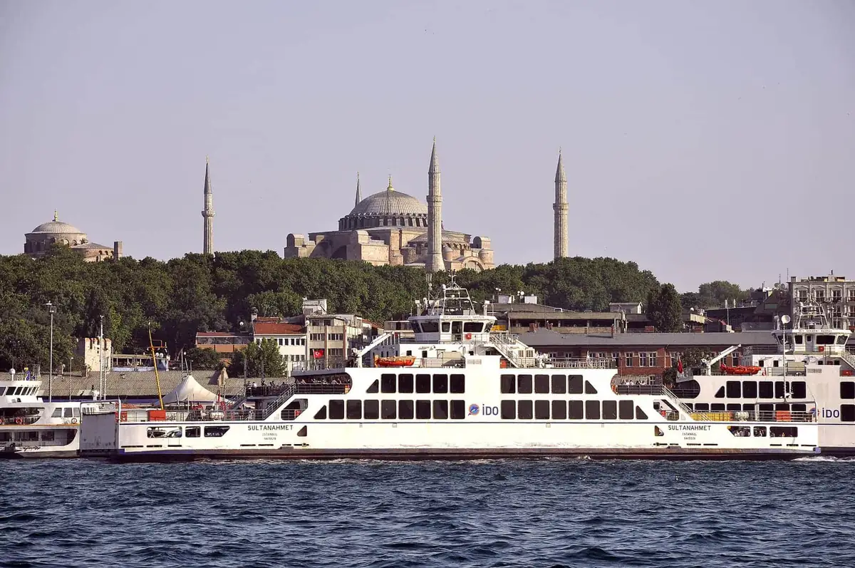 A white commuter ferry crossing the Bosphorus with domes and minarets behind