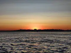 The domes and minarets of the old city silhouetted against an orange sunset over the water