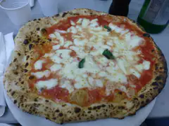 A Neapolitan Margherita pizza with a puffy charred crust on a marble table