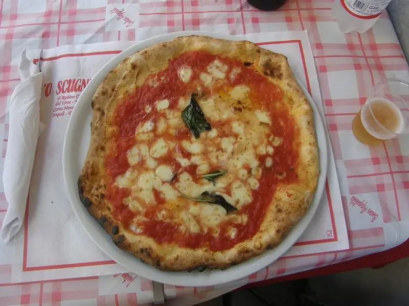 A Neapolitan pizza with tomato, fior di latte and basil on a checked tablecloth