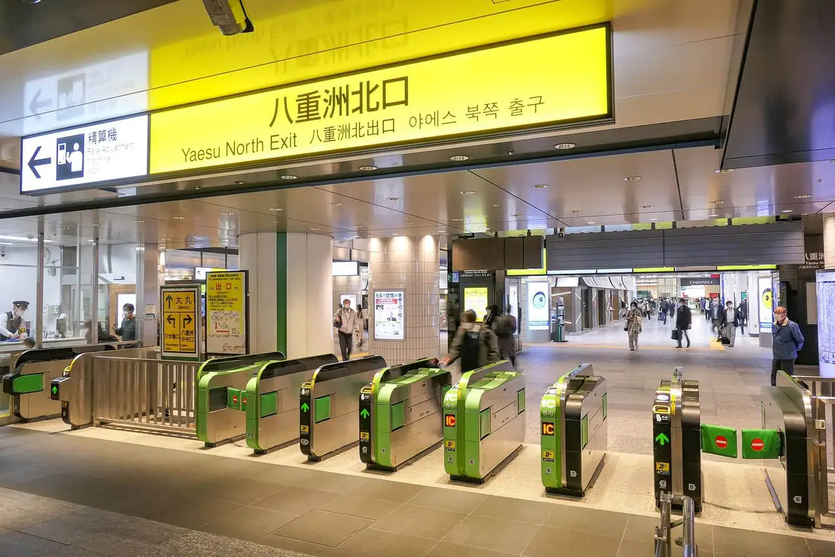 Ticket gates at Tokyo Station under the Yaesu North sign, with IC card readers and fare adjustment signs