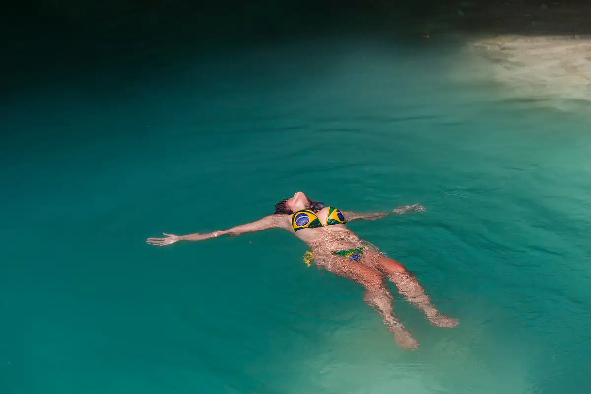 A swimmer floating in the clear turquoise water of a Homun cenote