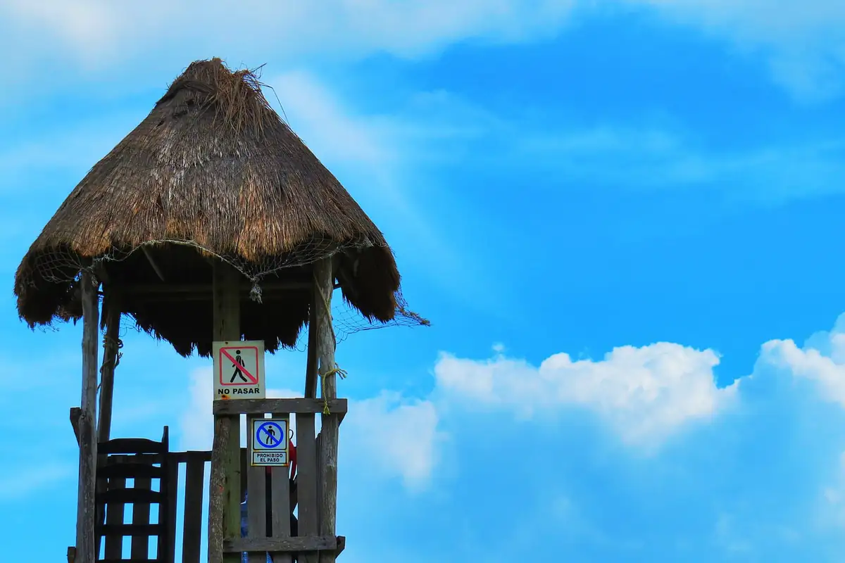 A palapa lifeguard tower with no-entry signs