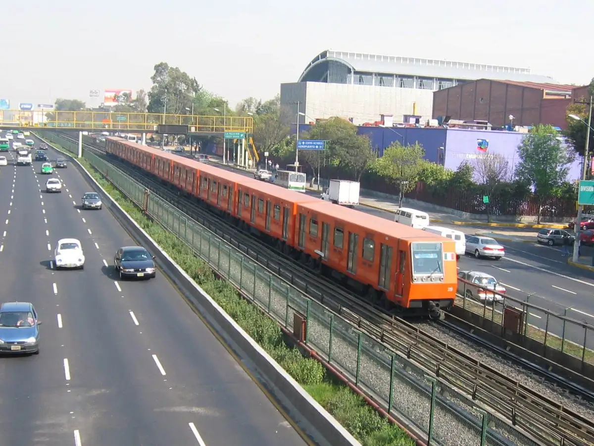An orange Metro train running above the avenue