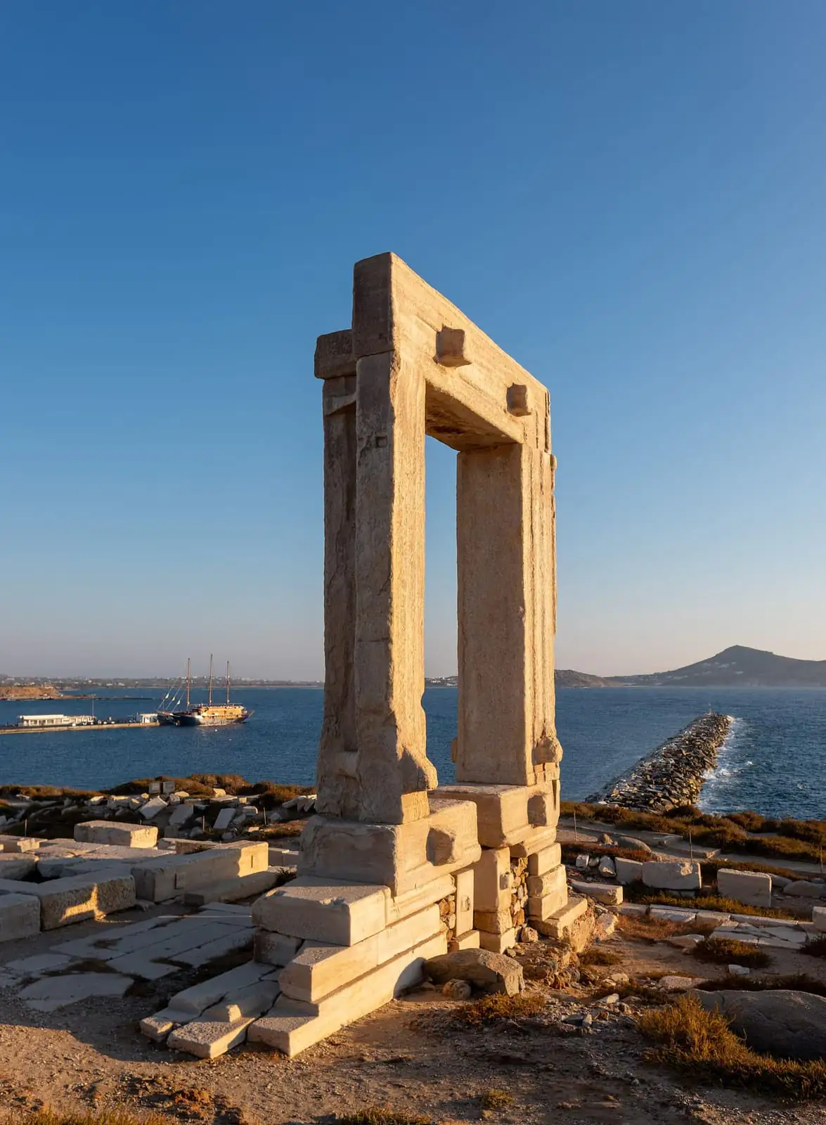 The marble doorway of the Portara temple standing above the sea on Naxos at golden hour