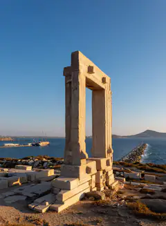 The marble doorway of the Portara temple standing above the sea on Naxos at golden hour