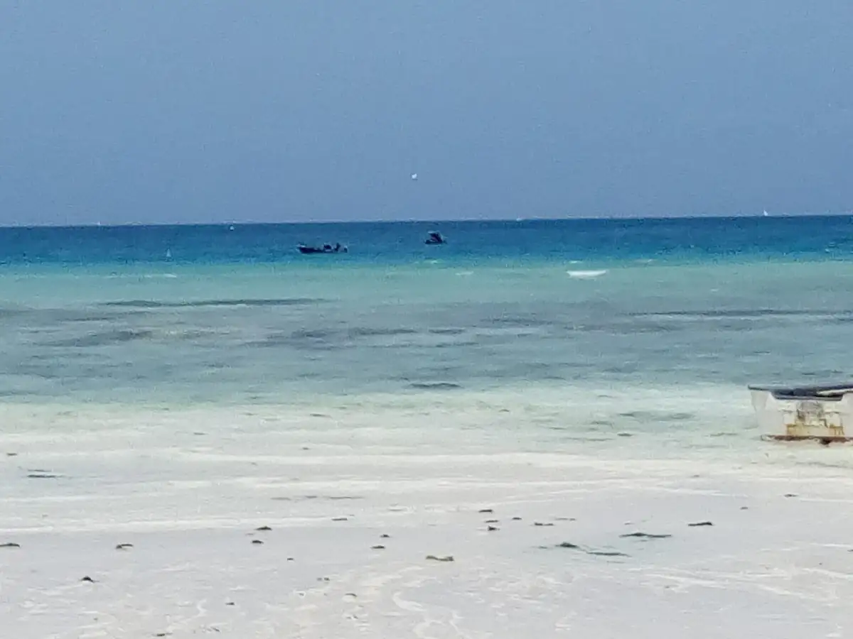 White sand and turquoise shallows with boats anchored offshore