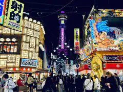 Tsutenkaku Tower lit up at night above the crowded neon streets of Shinsekai