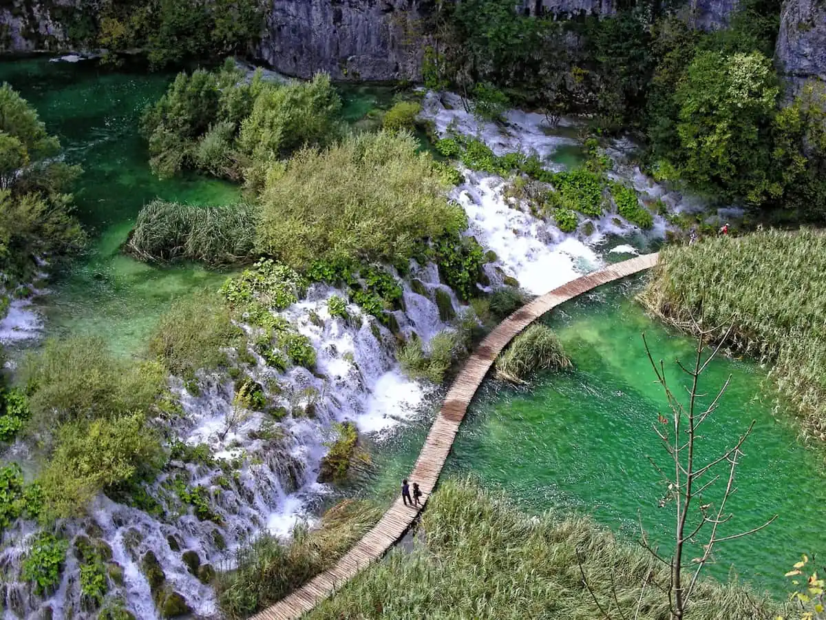 Boardwalk curving between cascades and green pools at Plitvice