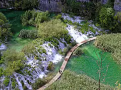 Boardwalk curving between cascades and green pools at Plitvice