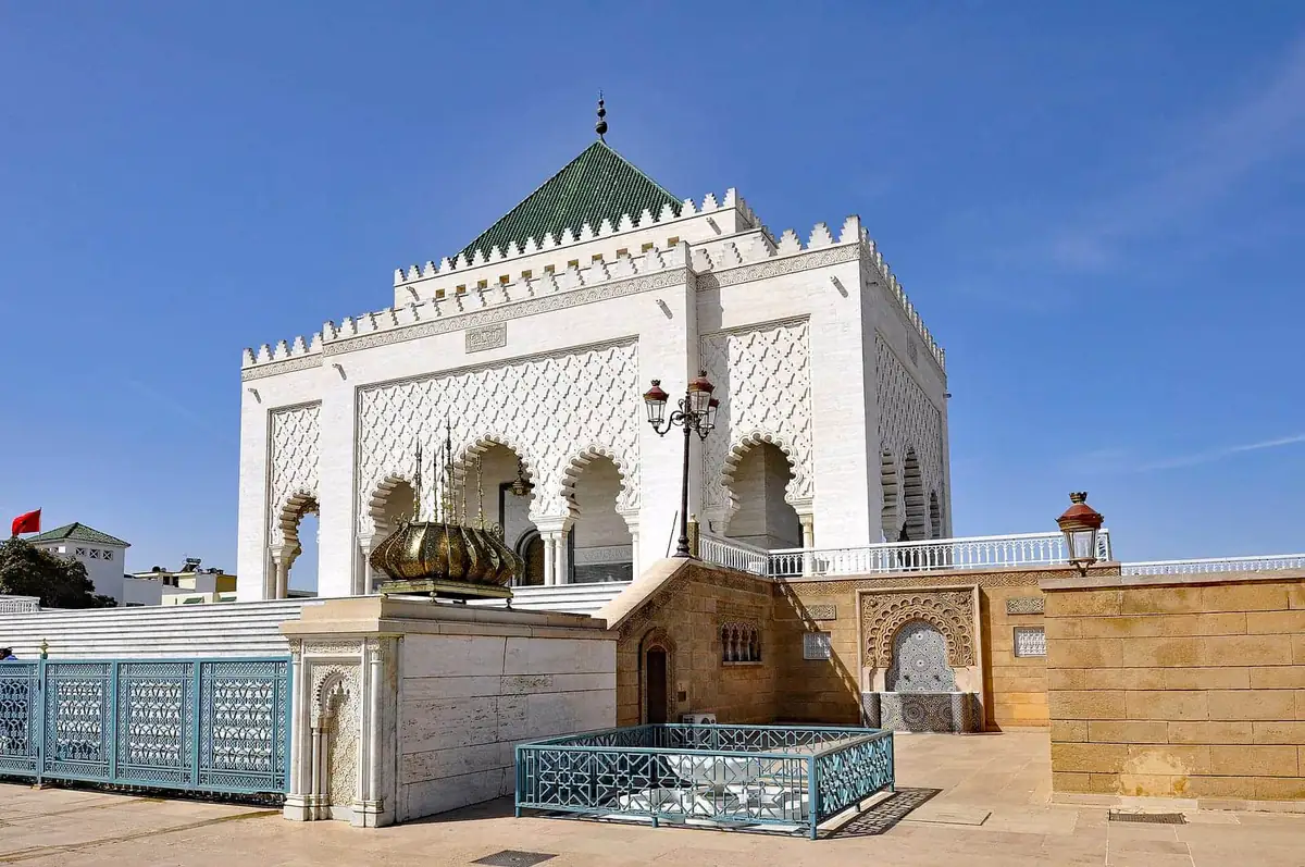 The white marble Mausoleum of Mohammed V with its green tiled pyramidal roof and carved arched facade in Rabat