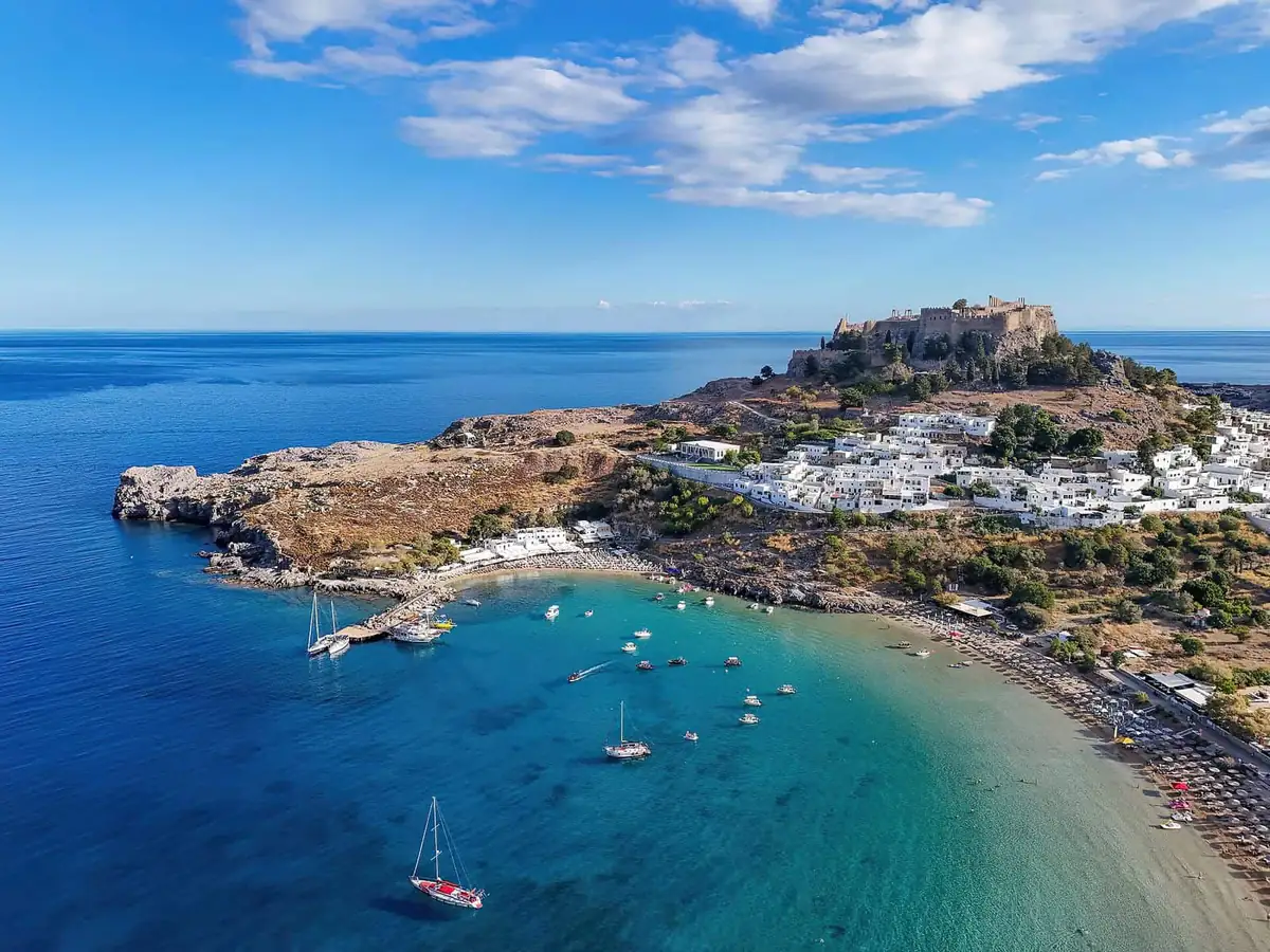 Aerial view of Lindos with its acropolis above the white village and turquoise bay