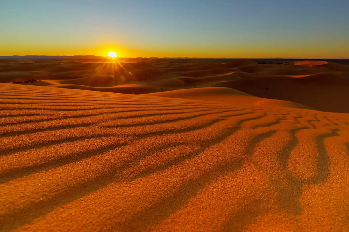 Sun setting over rippled sand ridges in Erg Chebbi