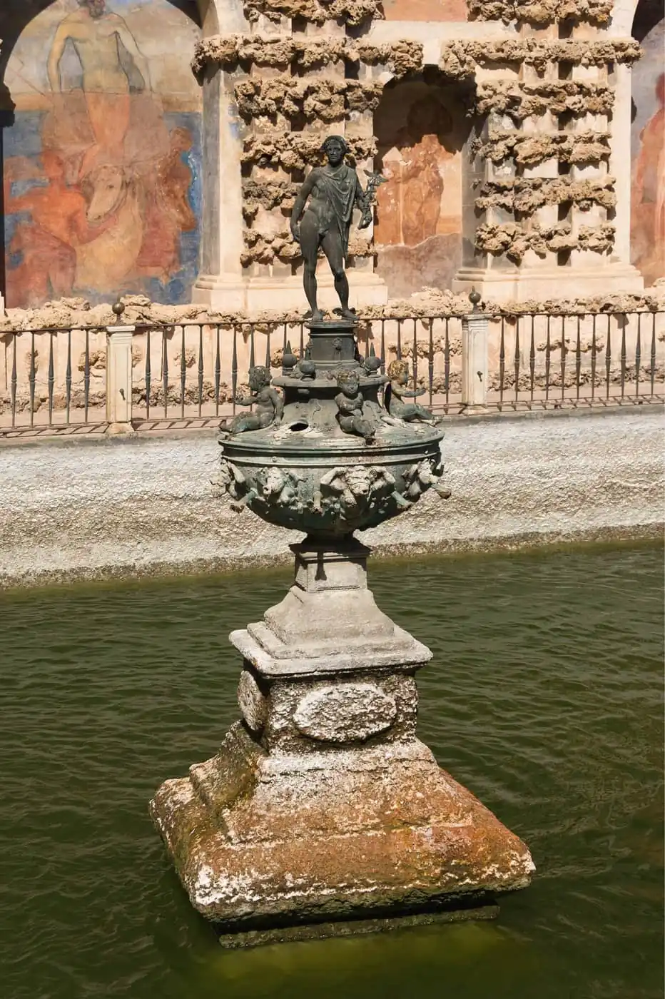 The bronze Mercury fountain in the gardens of the Alcazar in Seville, with painted frescoes behind