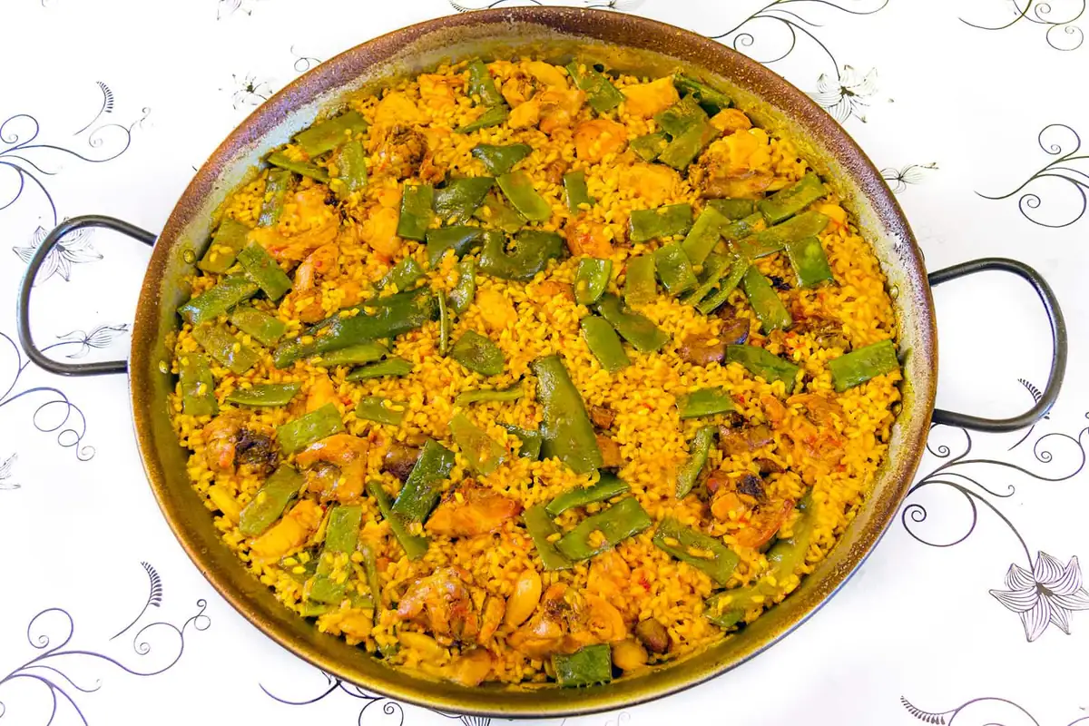 A traditional Valencian paella with chicken and green beans in the pan