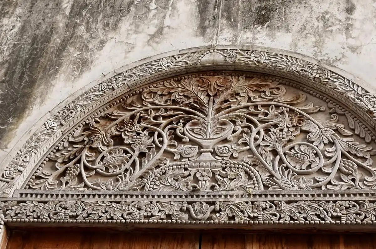 Carved floral lintel above a wooden door in a Stone Town alley