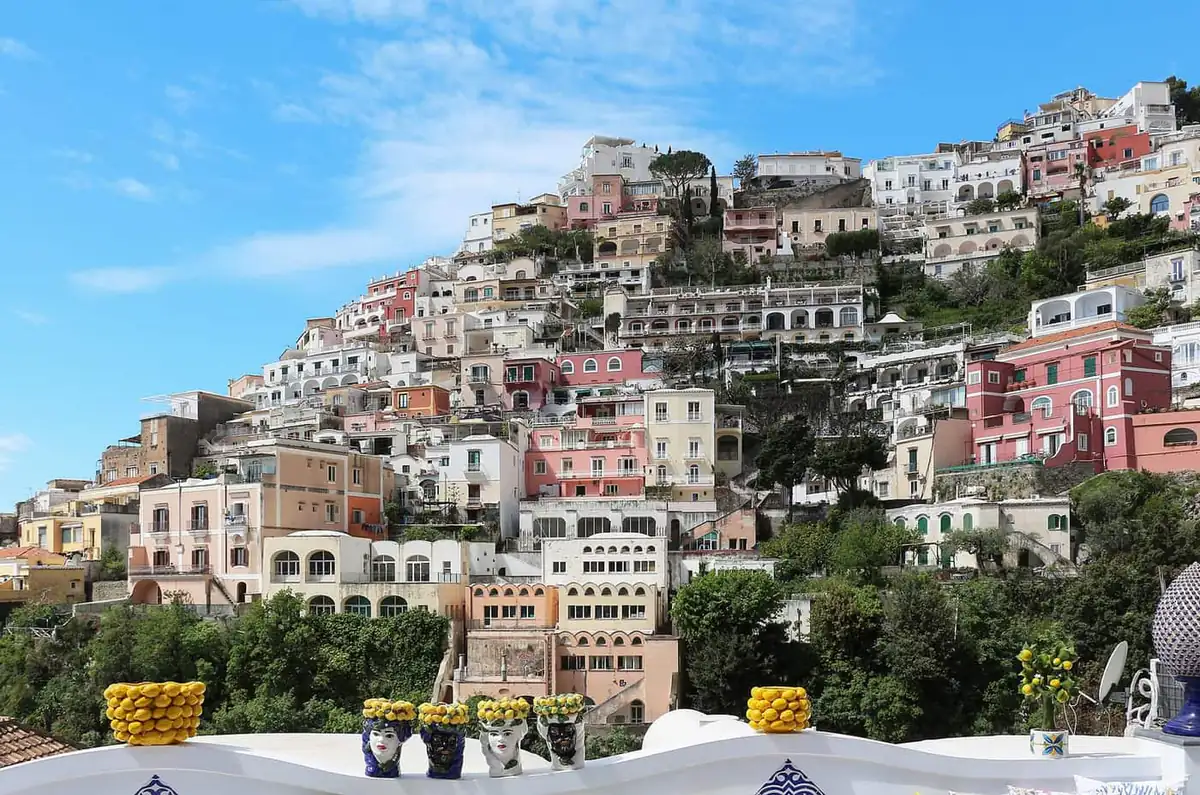 Terraced hillside houses in Positano seen from a terrace with ceramic figures in the foreground