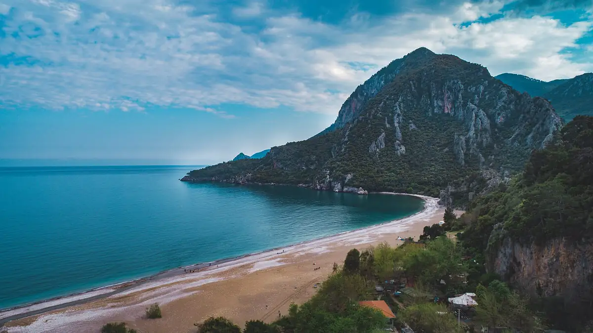 Curved sandy bay backed by steep pine-covered mountains
