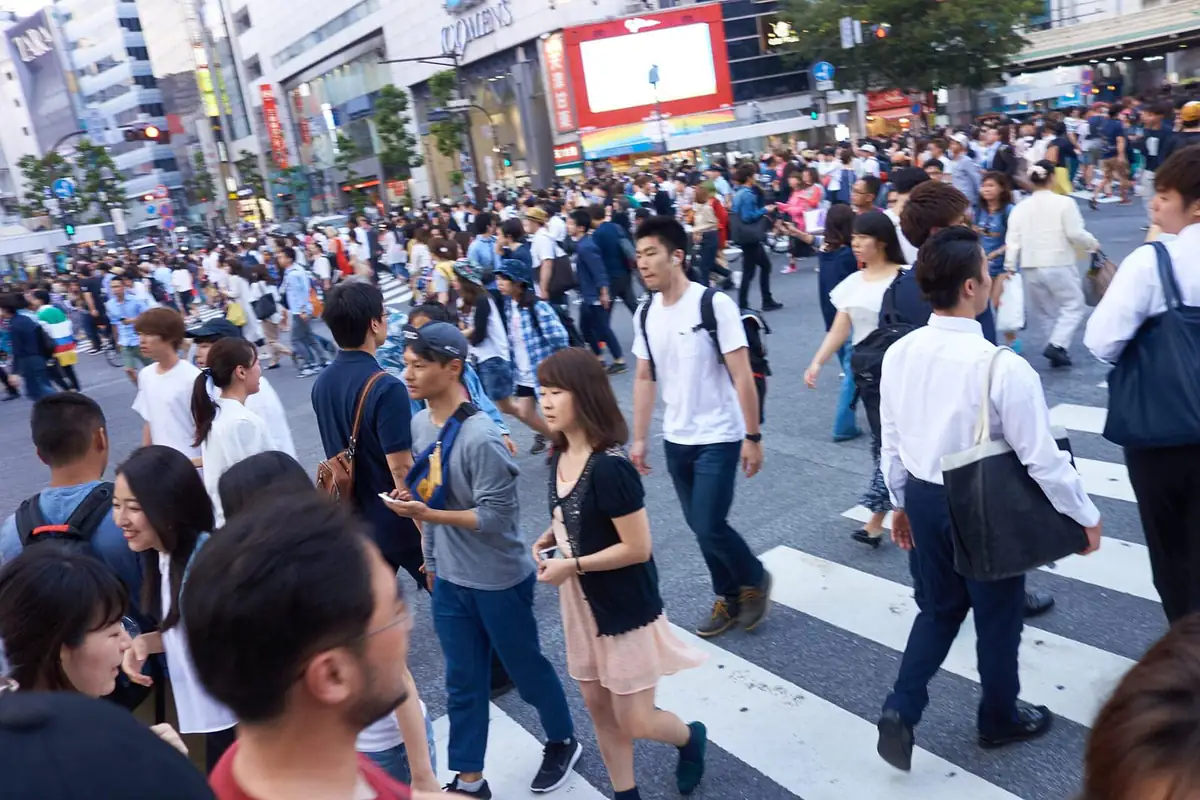 Pedestrians crossing Shibuya's Scramble Crossing, with the neon-lit buildings behind