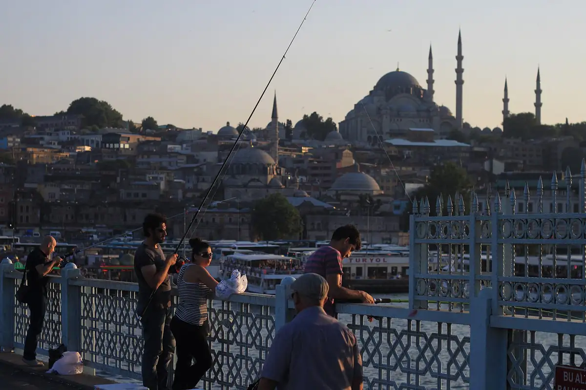 Fishermen on Galata Bridge at sunset with Suleymaniye Mosque behind