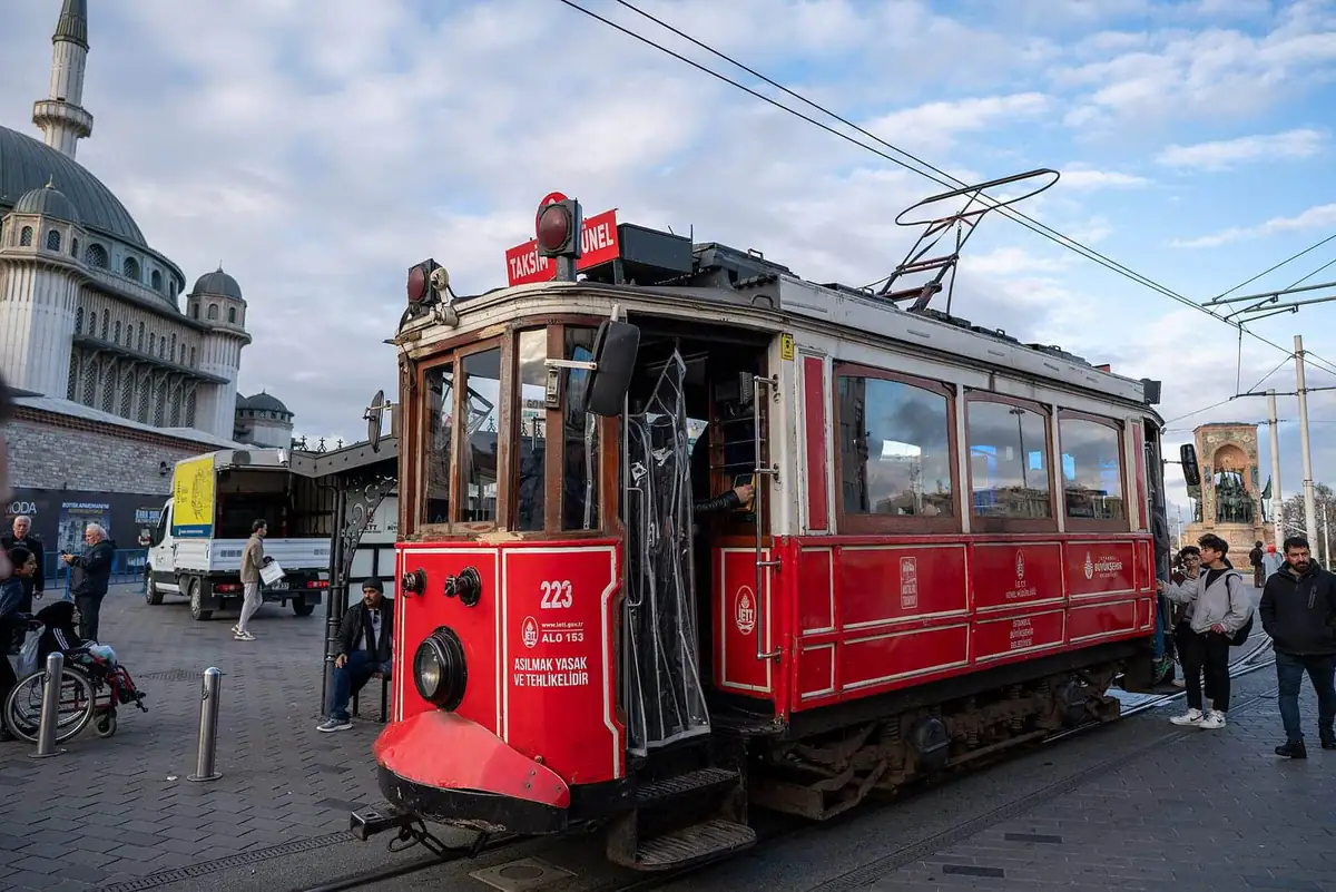 The red nostalgic tram at Taksim with a mosque behind