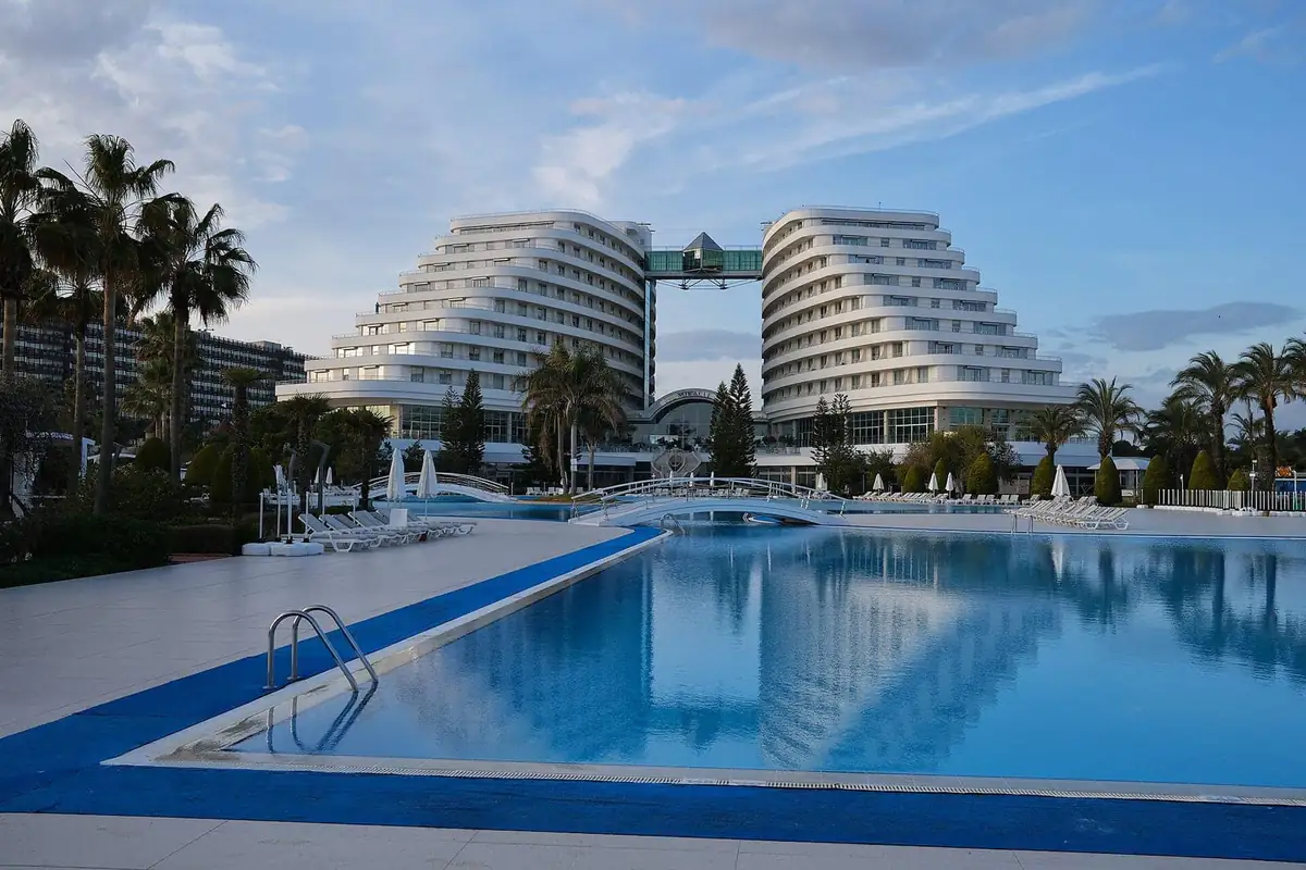 Twin resort blocks and a long pool on the Lara coast at dusk