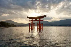 The vermilion torii of Itsukushima Shrine standing in the sea off Miyajima at sunset