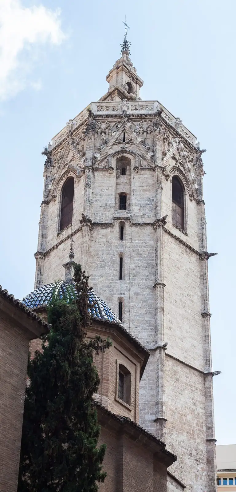 The octagonal Miguelete bell tower of Valencia Cathedral seen from below, with blue tiled cupolas in the foreground
