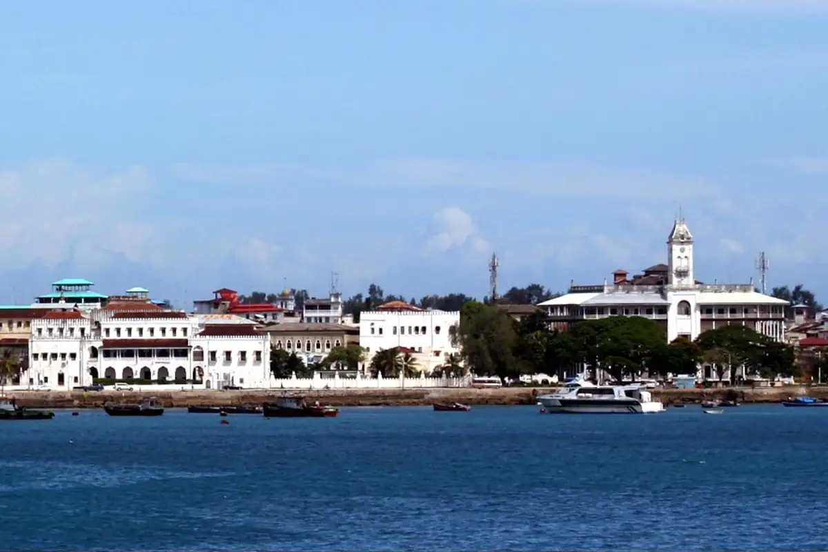 Stone Town waterfront with white palace buildings and boats on blue water